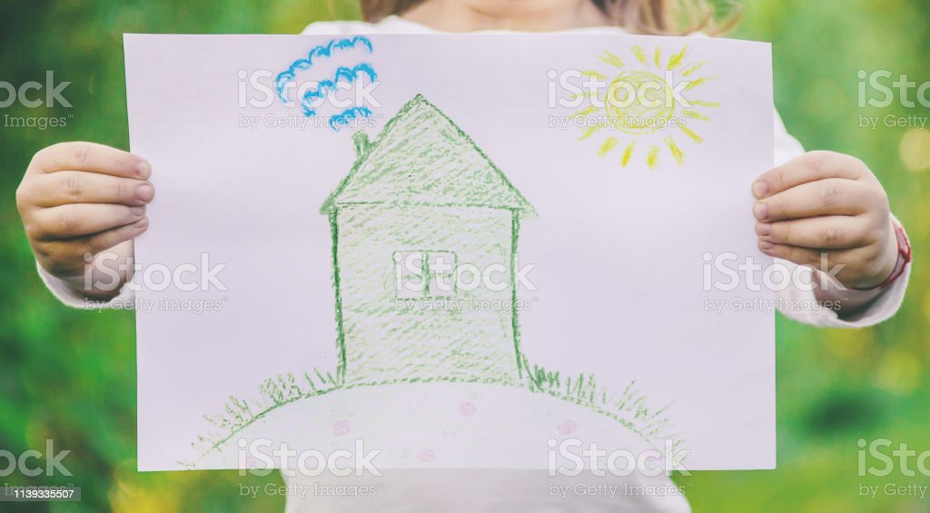 Drawing of a green house in the hands of a child. nature.l